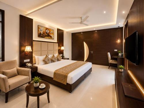 a hotel room with a bed and a chair and a television at Hotel Sai Jashan Shirdi - Where blessings & comfort meet in Shirdi