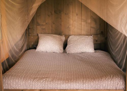 a bed with two pillows on top of it at Lodge Holidays - Les Sapins in Camurac