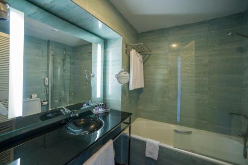 
a bathroom with a sink, mirror, and bathtub at Vila Gale Ampalius in Vilamoura
