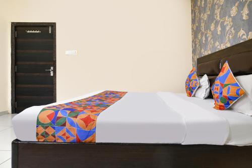 a bedroom with a white bed with colorful pillows at FabHotel Shree I in Indore