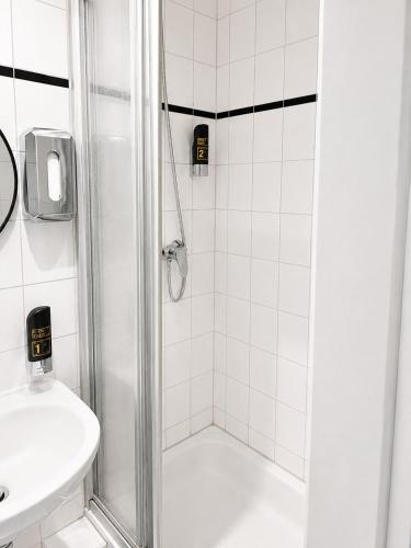 a white bathroom with a shower and a sink at Hotel Alameda in Hamburg