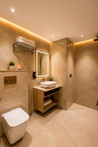 a bathroom with a toilet and a sink and a mirror at The Aura Hotel & Resort in Noida
