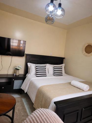 a bedroom with two beds and a tv on the wall at Faymu Homes in Kitengela 