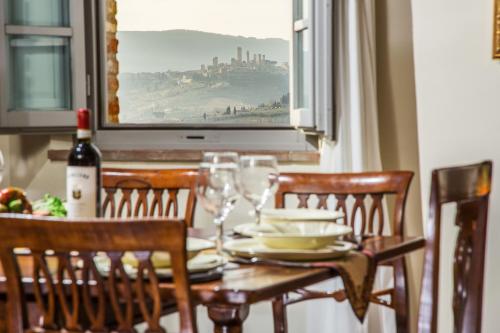a dining room table with glasses and a bottle of wine at Castello di Fulignano Sinadra superior apartment in San Gimignano