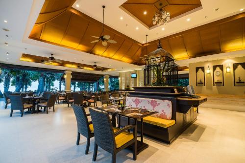 a dining room with tables and chairs in a restaurant at Ravindra Beach Resort & Spa - SHA Extra Plus in Na Jomtien