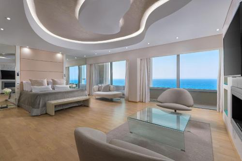 a bedroom with a bed and a living room with the ocean at Rodos Palace Hotel in Ixia