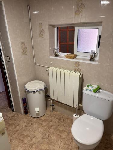 a bathroom with a white toilet and a window at Casa villada in Villada