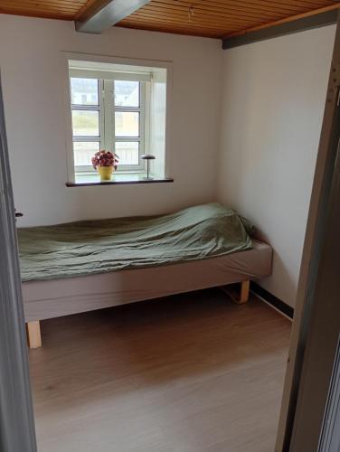 a small bedroom with a bed and a window at Vesterhavet in Nørre Vorupør