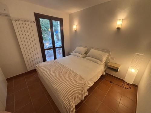 a bedroom with a bed with white sheets and a window at Condominio Villa Helios in Cuasso Al Monte