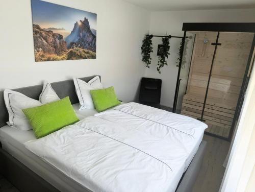 a white bed with green pillows in a room at Sauna Apartment Adelina Bad Wörishofen in Bad Wörishofen