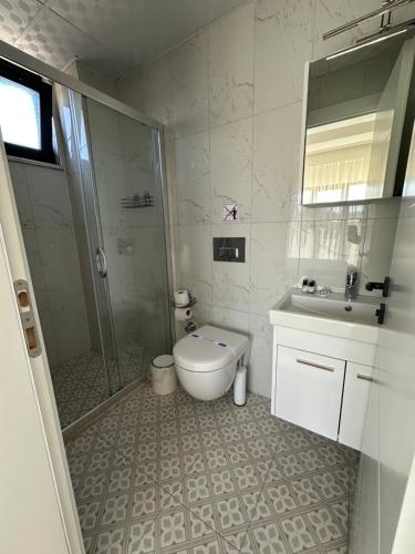 a bathroom with a shower and a toilet and a sink at Sevgi Hotel in Ezine