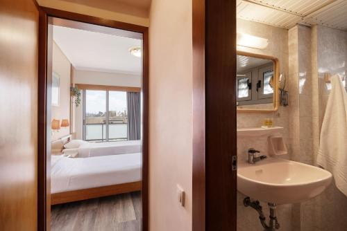 a bathroom with a sink and a bed and a mirror at Xenophon Hotel in Athens