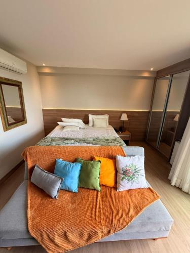 a bedroom with a large bed with colorful pillows at Vista Azul Hotel Frente Pedra Azul in Pedra Azul