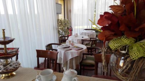 ein Restaurant mit zwei Tischen und Stühlen mit roten Blumen in der Unterkunft Corte Degli Estensi in Formigine