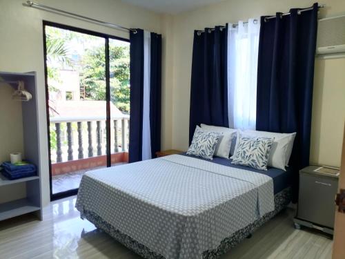 a bedroom with a bed with blue curtains and a balcony at Solsken Guest House - Bantayan Island in Bantayan Island
