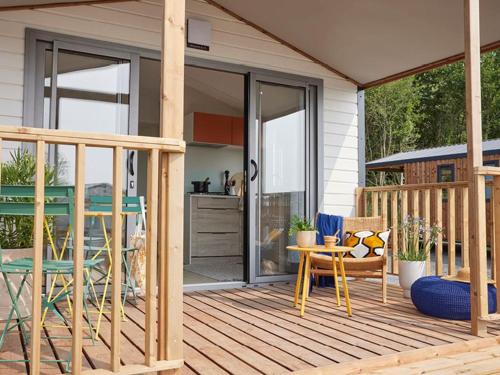 a wooden deck with a table and chairs on a house at CAMPING PLEIN SOLEIL in Lourdes