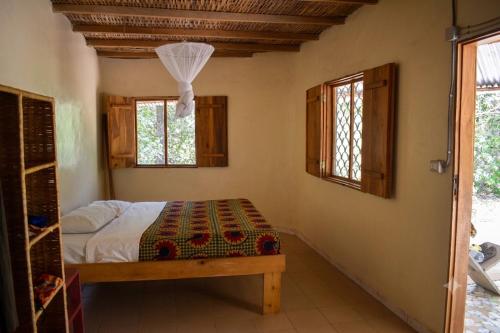 a bedroom with a bed and two windows at Campement solidaire Nioko Bokk in Abémé