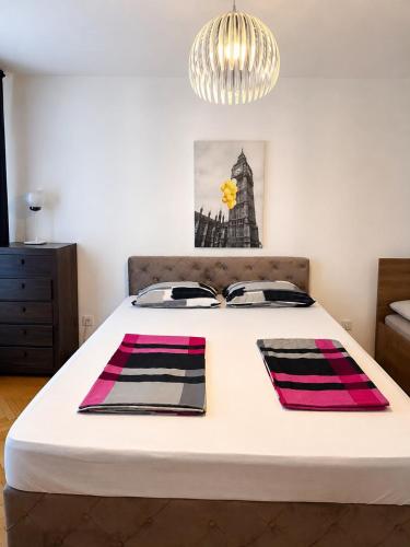 a bedroom with a large white bed with a chandelier at Apartment CenterZeroZone in Banja Luka