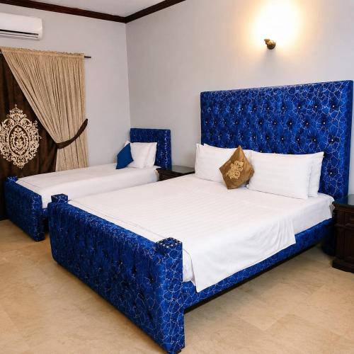 two beds in a room with blue furniture at Beach Heaven Guest House in Karachi