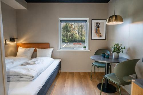 a bedroom with a bed and a table and a window at MyHotel Taastrup in Tåstrup