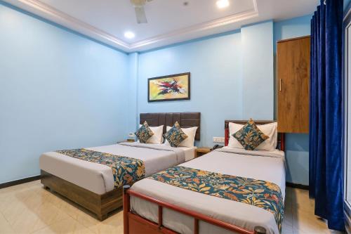 two beds in a room with blue walls at FabHotel Maple Leaf in Hyderabad