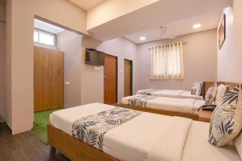 a bedroom with three beds and a television in it at FabHotel Maple Leaf in Hyderabad