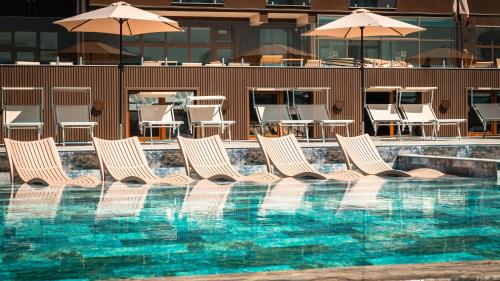 a group of chairs and umbrellas next to a swimming pool at Németh Resort in Sovata