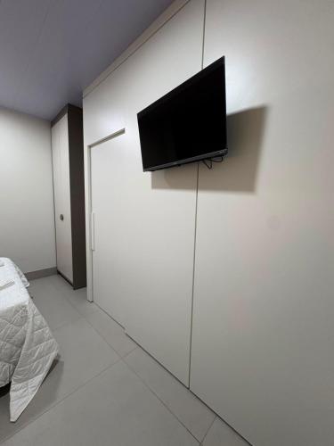 a bedroom with a tv on a white wall at Estúdio J&C 05 A in Primavera do Leste