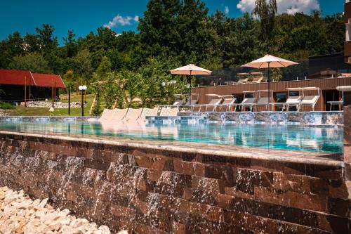 a large swimming pool with chairs and umbrellas at Németh Resort in Sovata