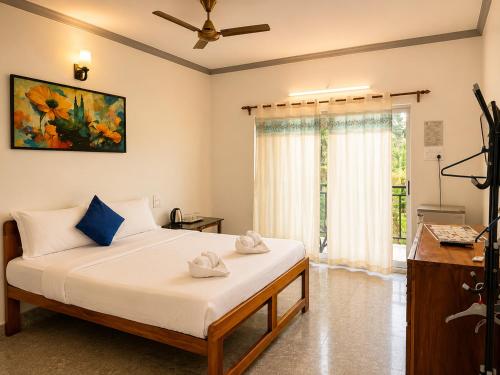 a bedroom with a bed with a ceiling fan and a window at Casa de Arambol in Arambol