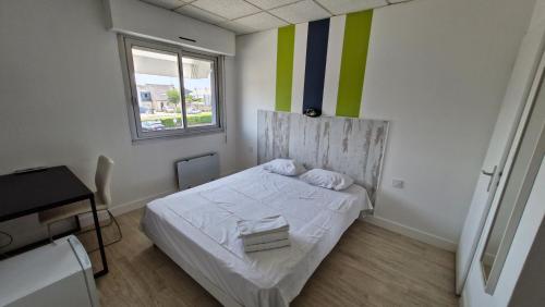 a small bedroom with a white bed and a window at Hotel Le Rohu Vannes in Séné