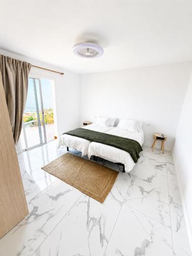 a white bedroom with a bed and a marble floor at Nido del Sol in Guía de Isora
