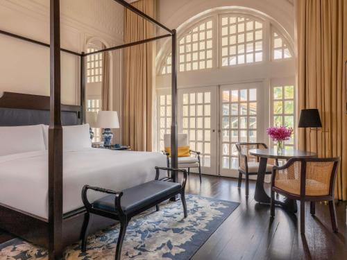 a bedroom with a bed and a table and chairs at Raffles Singapore in Singapore
