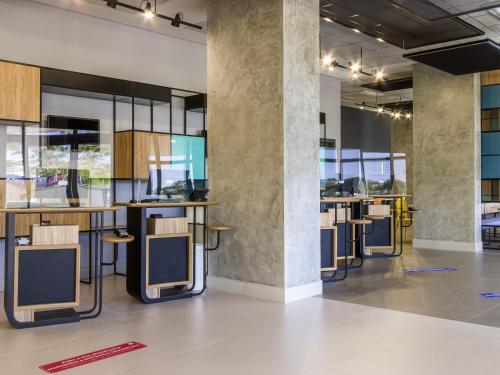 a row of bar stools in a room with windows at ibis Ribeirao Preto Vila do Golf Shopping in Ribeirão Preto