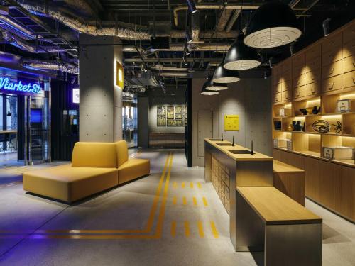 a lobby with a yellow couch and a counter at ibis Styles Nagoya in Nagoya