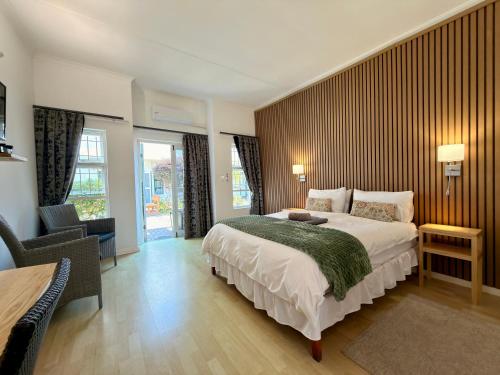 ein Schlafzimmer mit einem großen Bett und einem Stuhl in der Unterkunft Langholm Hotel in Walvis Bay