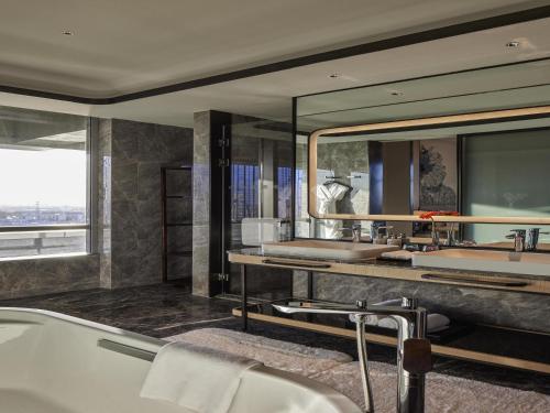a bathroom with two sinks and a large mirror at Pullman Suzhou Taicang in Taicang