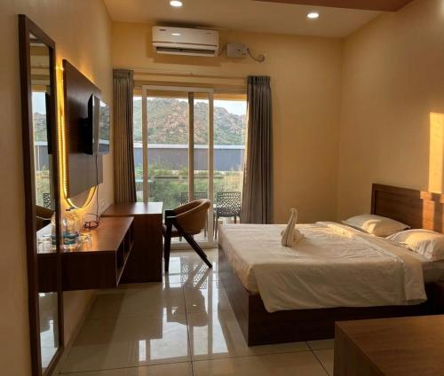 a bedroom with a bed and a desk and a television at Hotel Srirangasthalam in Chitradurga