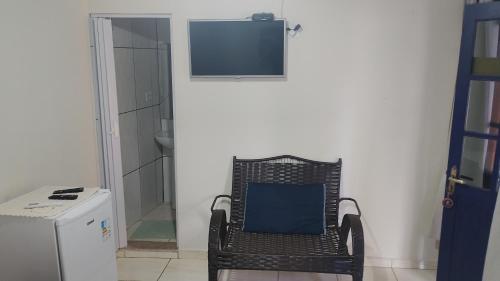a wicker chair sitting in a room with a television at Trindade Flat Azulmar in Trindade