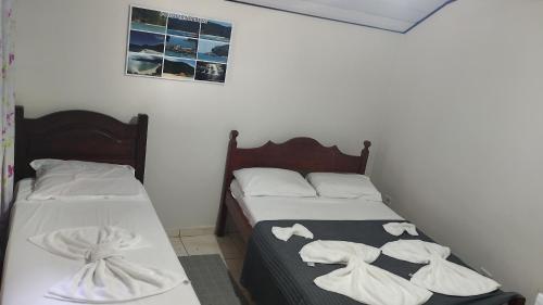 two beds in a room with white towels on them at Trindade Flat Azulmar in Trindade