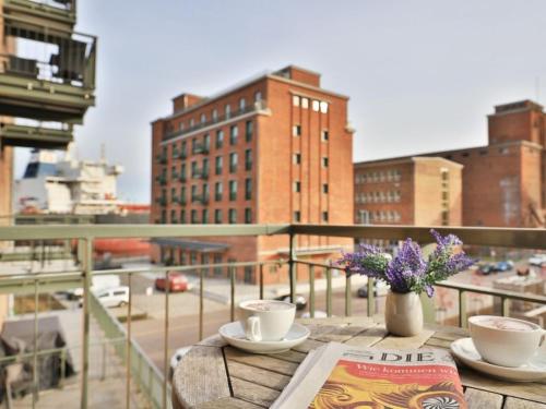a table with two cups and a book on a balcony at Ohlerich Speicher App_ 10 in Wismar