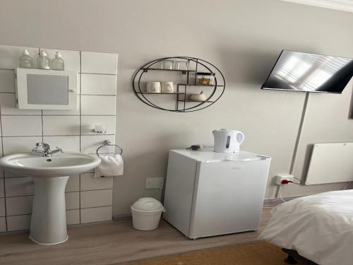 a small white bathroom with a sink and a refrigerator at Grace Walk Guest House in Swellendam
