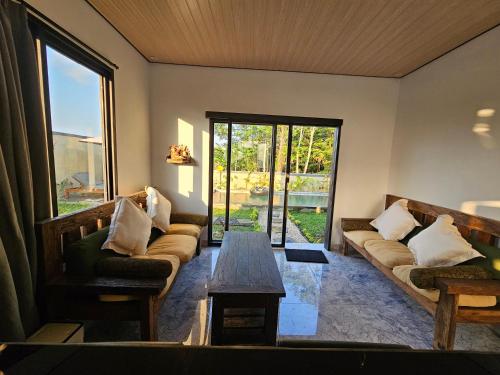a living room with couches and a table and a window at Kala Senja Guest House in Sukawati