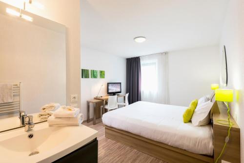 - une chambre avec un lit, un lavabo et un miroir dans l'établissement Ténéo Apparthotel Bordeaux Mérignac Aéroport, à Mérignac