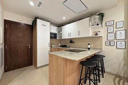 a kitchen with white cabinets and a counter with bar stools at Antika Marbella 1A in Marbella