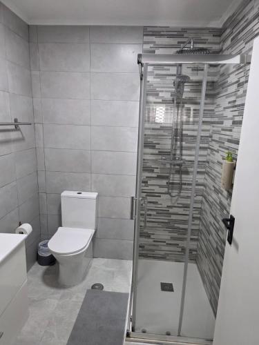 a bathroom with a toilet and a glass shower at Mikaela Guest House in Odivelas