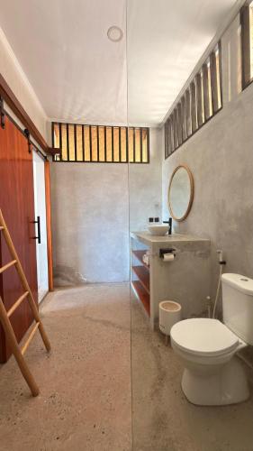 a bathroom with a toilet and a sink and a mirror at The Villa Indah Areguling in Kuta Lombok