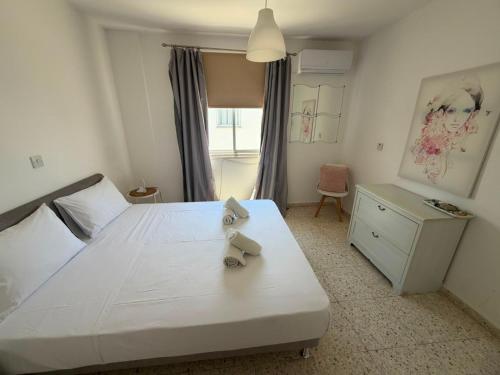 a bedroom with a large white bed and a window at Riana Latchi Apartment in Polis Chrysochous