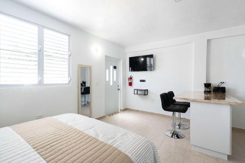a white bedroom with a bed and a desk at Colmado by Otium in Hato Candal