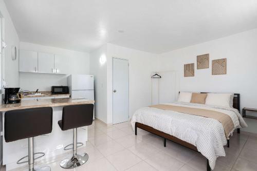 a white bedroom with a bed and a kitchen at Colmado by Otium in Hato Candal